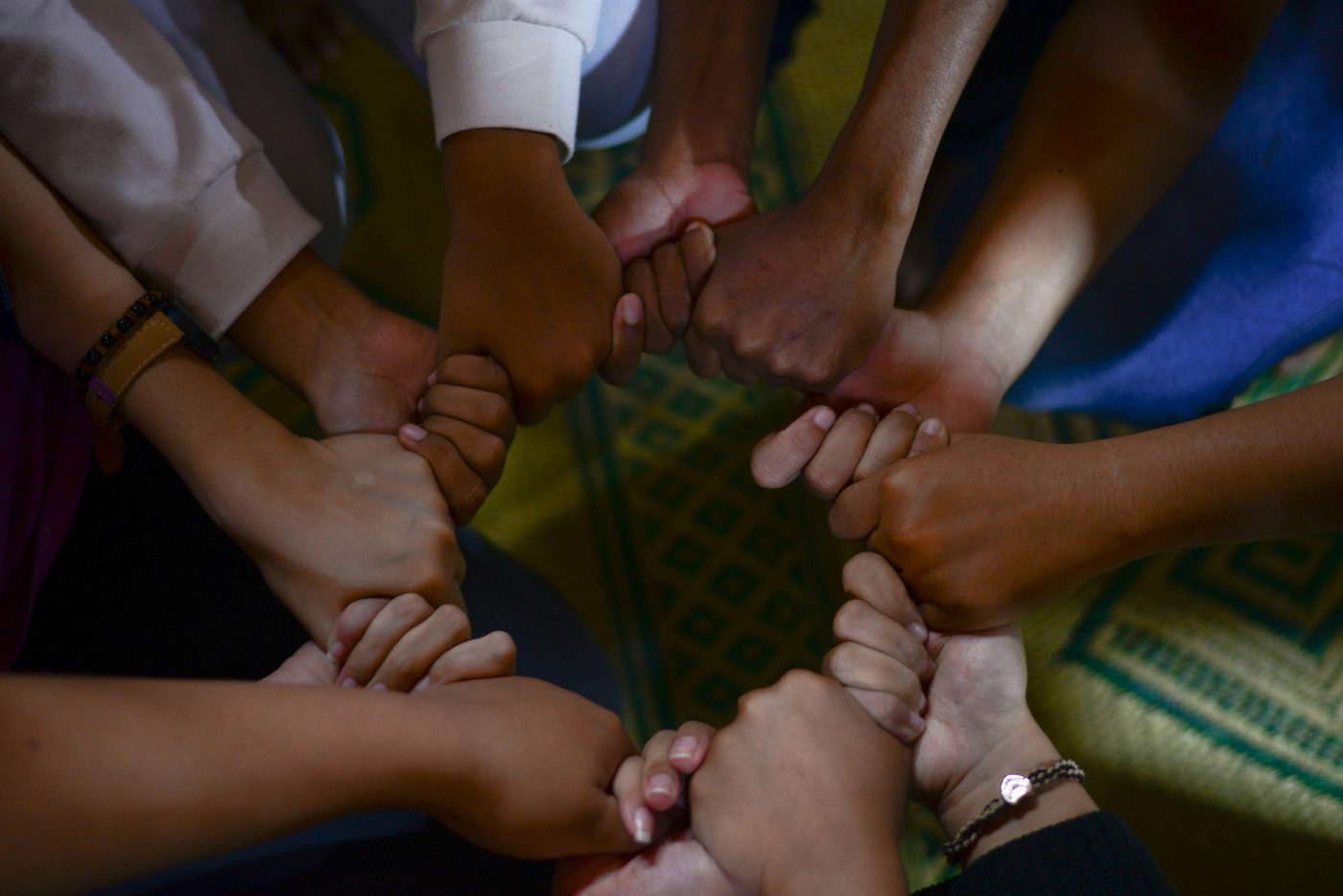 A circle of diverse hands clasped together in support